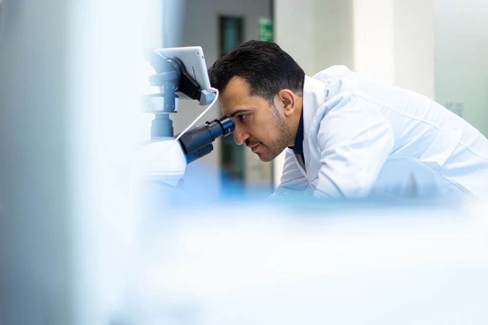 Archival photograph of Dr. Farshad Goodarzi conducting microscopy